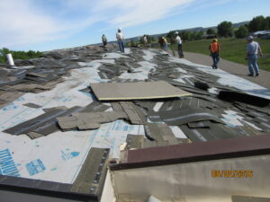 Shingles torn off the existing Huntley Project High School roof lie in the foreground as workers look over another part of the roof on June 3. (photo courtesy of Dane Bradford/HP Schools)